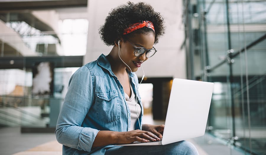 Pretty young black lady wearing glasses working on a laptop